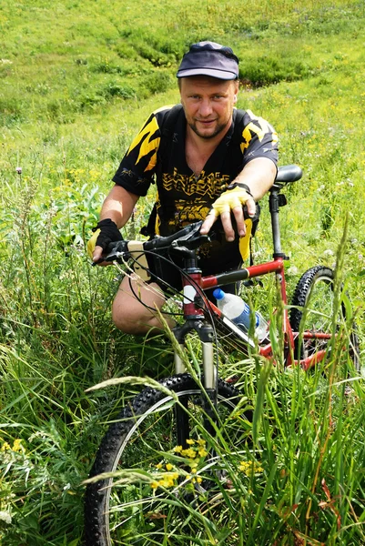 Mountainbiker wacht op groen veld — Stockfoto