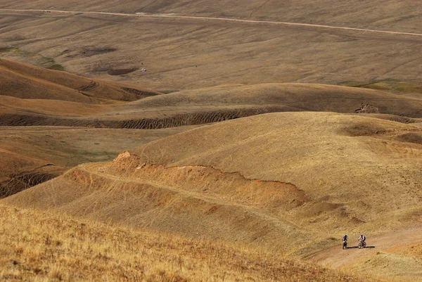 Two mountain bikers on old road in desert mounta — Stock Photo, Image