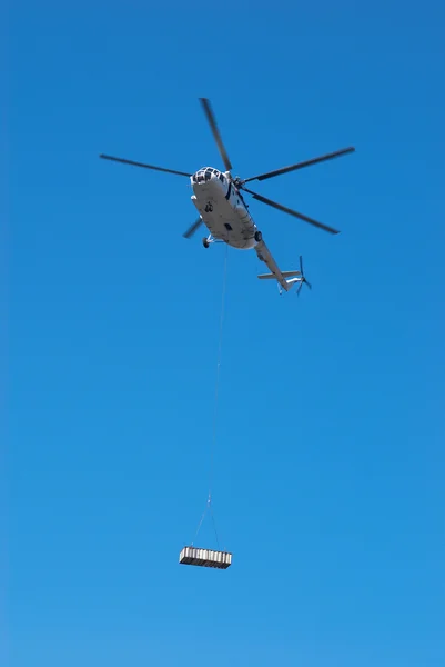 Fly helicopter with cargo on rope — Stock Photo, Image