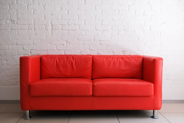Röd soffa och vit tegelvägg — Stockfoto