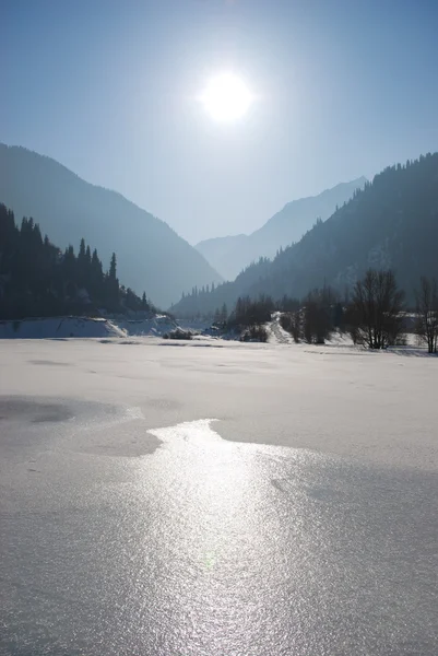 Зимнее горное озеро и солнце — стоковое фото