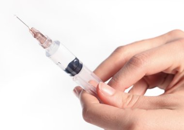 Hand holding a syringe of medicine clipart