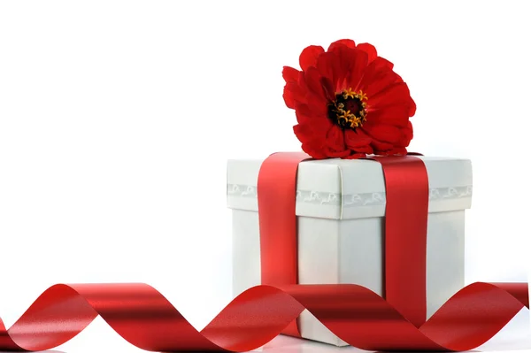 Подарок с красной лентой и цветком — стоковое фото