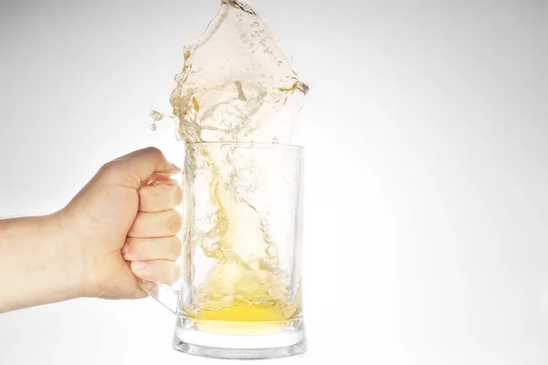 Hand som håller Mugg med stänk öl — Stockfoto