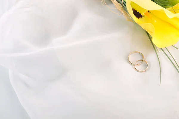 Lirios de cala amarillos y anillos de boda — Foto de Stock