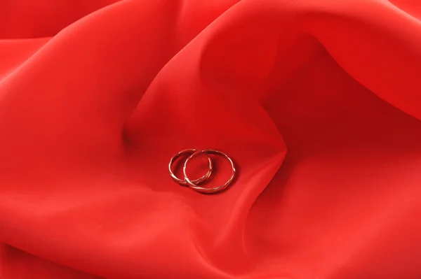 Tecido vermelho e anéis de casamento — Fotografia de Stock