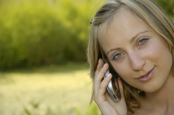 Leuk meisje op het gras-perceel met mobiele telefoon — Stockfoto