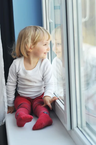 Flickan sitter vid fönstret — Stockfoto