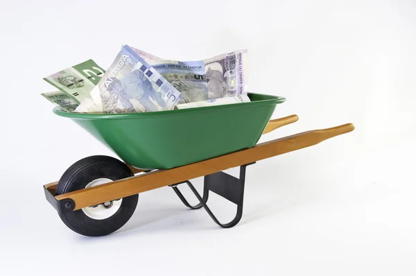 Green wheel barrel full of dollar bills — Stock Photo, Image