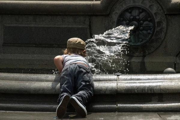 Kleiner Junge spielt auf einem Brunnen — Stockfoto