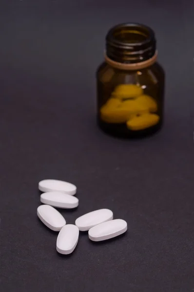 Pílulas de medicina e uma garrafa no escuro — Fotografia de Stock