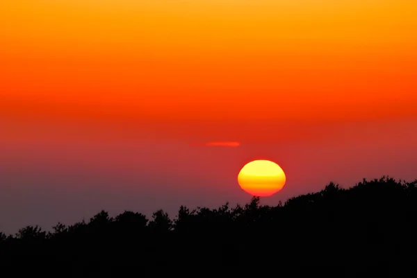 Una vibrante puesta de sol naranja y dorada en la región montañosa — Foto de Stock