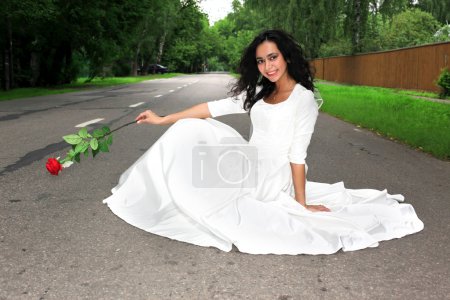 Mariée avec fleur rouge assis à la route 