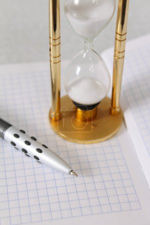 Verre à sable avec le crayon et un noteboo 