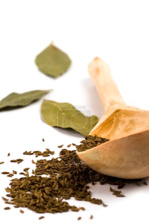 Cumin sur cuillère en bois et feuilles de laurier 
