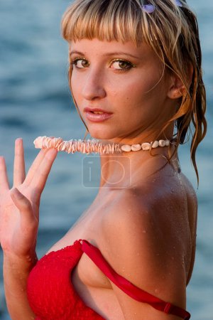 Femme tenant collier à la plage 