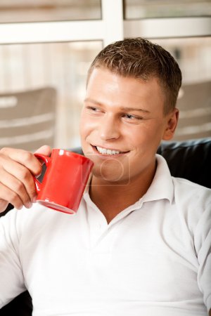 Un gars souriant qui boit du café 