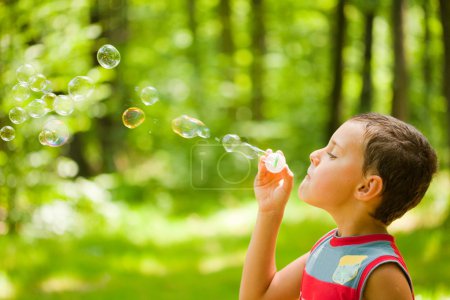 Mignon enfant soufflant des bulles de savon 